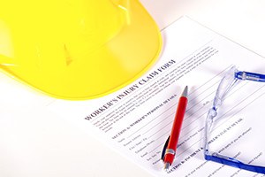 Worker injury claim hard hat with eyeglasses and pen on white background