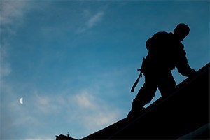 contractor in silhouette working on a roof top