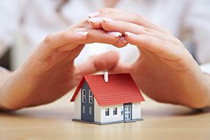 Female hands saving small house with a roof