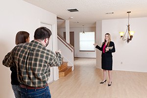 A female real estate agent shows an empty home to a husband and wife who are prospective buyers