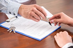 Young woman is signing financial contract with male realtor