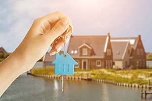 Woman Handing Over the House Keys in Front of a Beautiful New Home