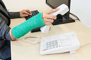 Injured businesswoman with green cast on the wrist holding telephone