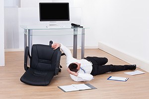 Full length of young businessman fallen from office chair